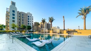 A swimming pool with lounge chairs and a clear view of surrounding buildings. - Maison Privee - Exclusive Luxury 3BR Apt with scenic views of Burj Al Arab (Dubai)