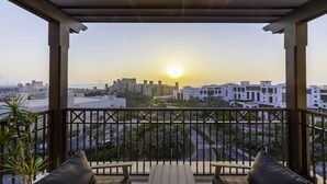 A balcony with a view of the cityscape at sunset, featuring modern buildings and a clear sky. - Maison Privee - Exclusive Luxury 3BR Apt with scenic views of Burj Al Arab (Dubai)