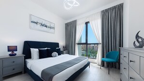 A modern hotel room with a large bed, a desk, a chair, and a view of the city. - Maison Privee - Exclusive Luxury 3BR Apt with scenic views of Burj Al Arab (Dubai)