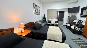 Een hotelkamer met twee bedden, een bank, een televisie, een kerstboom en een balkon.
