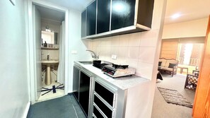 Een kleine keuken met een spoelbak, fornuis en kastjes.