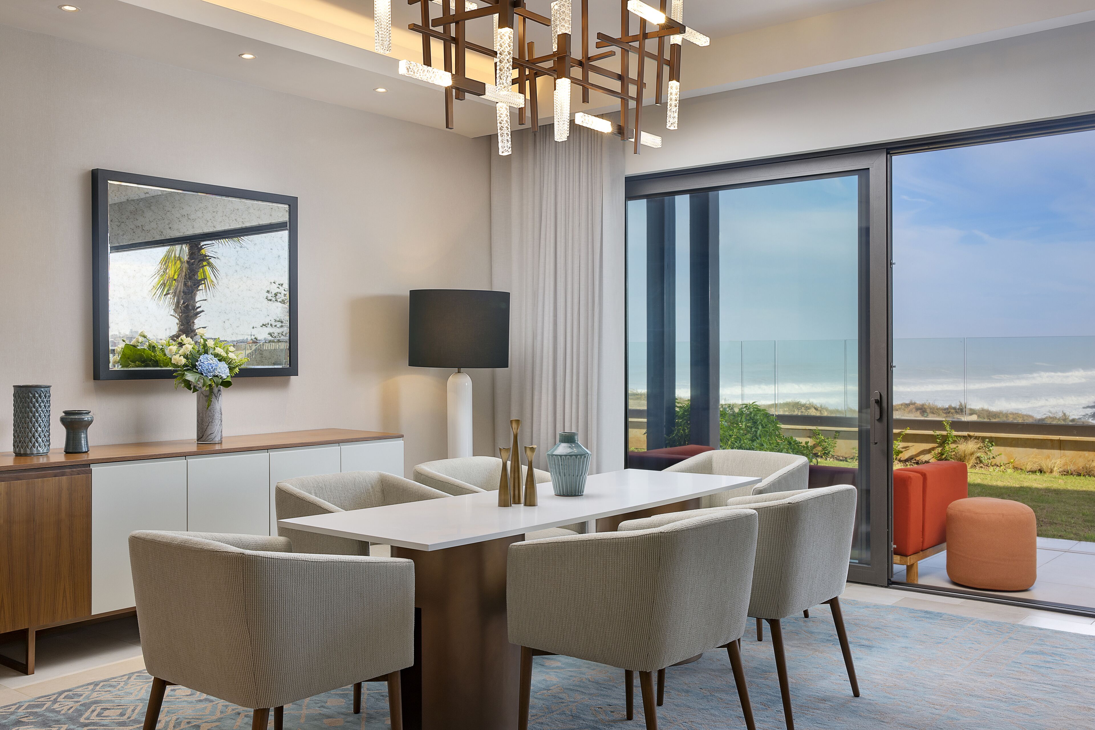 A modern dining area with a large table and chairs, a television, and a view of the outdoors.