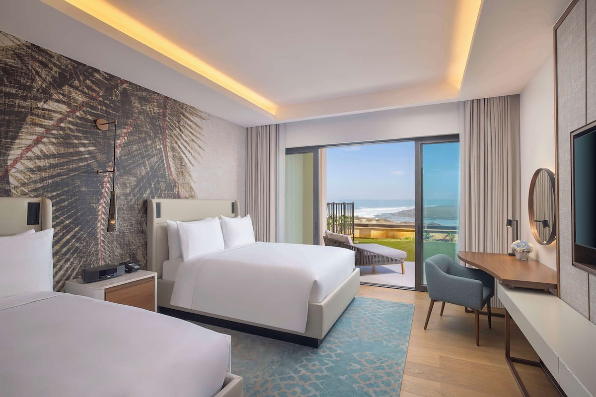 A modern hotel room with a large bed, a desk, and a view of the outdoors.