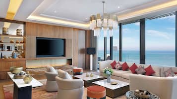 Una sala de estar moderna con un televisor de pantalla plana grande, asientos cómodos, una chimenea y vista al océano.