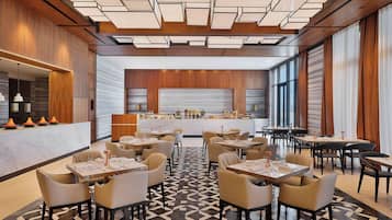 A modern restaurant with a geometric patterned floor, wooden panel walls, and a central bar area.