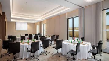 A conference room with multiple tables, chairs, and a large window providing a view of the outdoors.