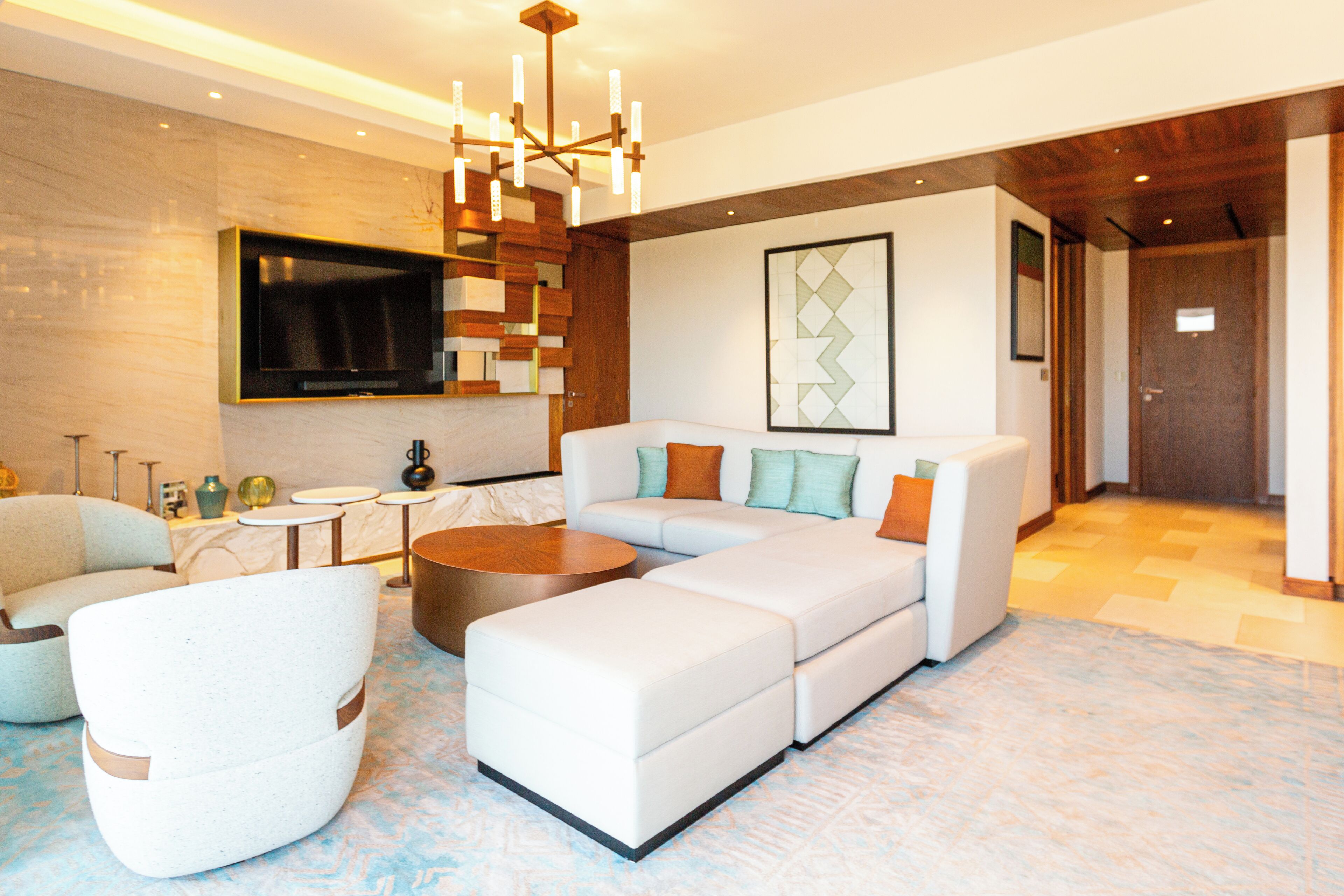 A modern living room with a sectional sofa, a coffee table, and a TV mounted on the wall.