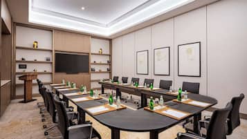A conference room with a long table, chairs, a podium, and framed artwork on the walls.