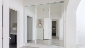 A room with a sliding glass door leading to a bathroom, a white door, and a light switch on the wall. - Elegant 2 bedrooms apt in Chelsea with patio (London)