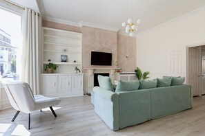 En moderne stue med sofa, lænestol, pejs og fjernsyn.