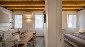 A modern kitchen with white cabinets, a wooden dining table, and a built-in oven. - Modern beach apartment with parking space (Chioggia)