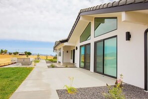 Een modern huis met een terras, grote ramen en uitzicht op het landschap.