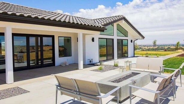 A modern house with a patio area featuring outdoor furniture and a fire pit.