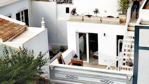 Un bâtiment blanc doté d’un balcon, d’une porte et d’une fenêtre.
