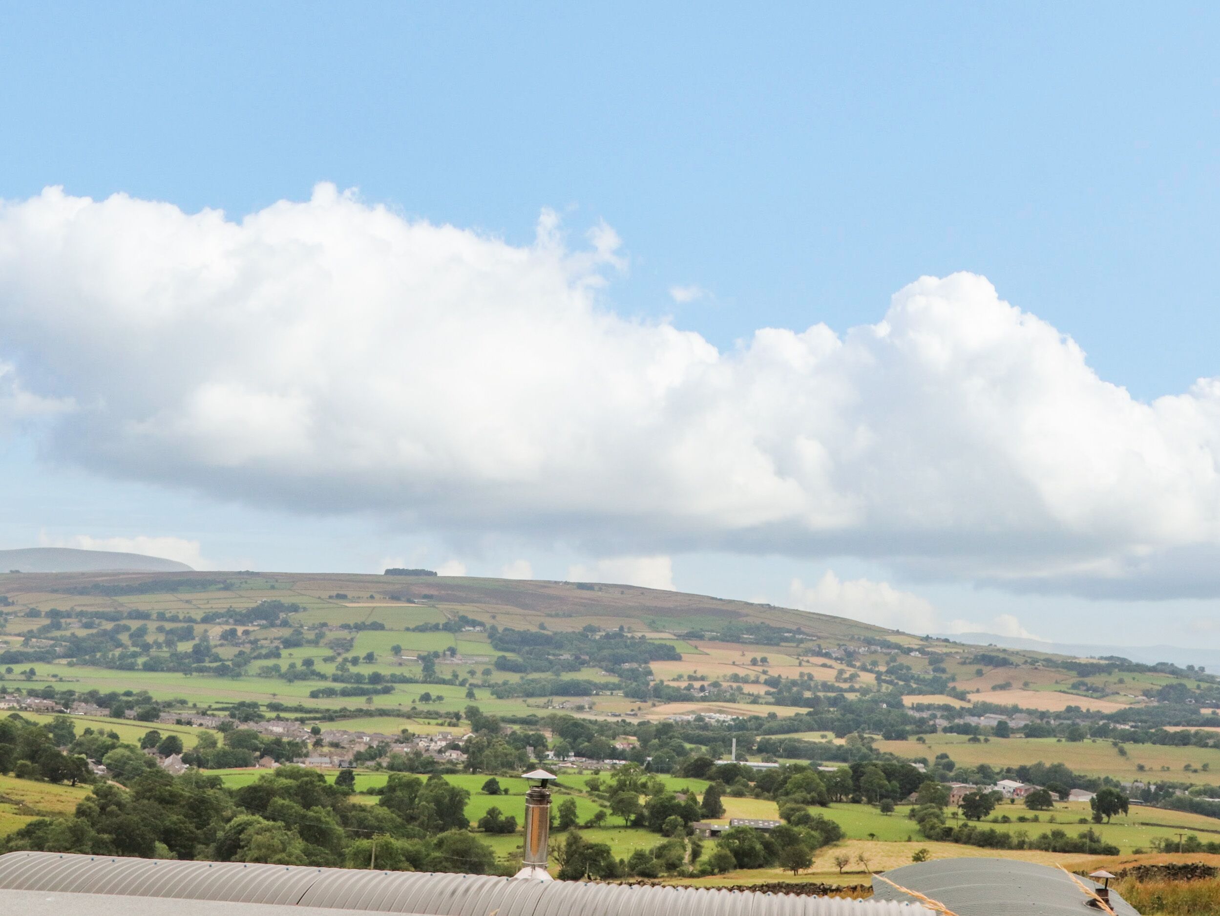 A rural landscape with rolling hills, scattered houses, and a prominent church steeple.