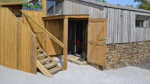 Een houten gebouw met een stenen fundering, een houten trap en een deur naar binnen.