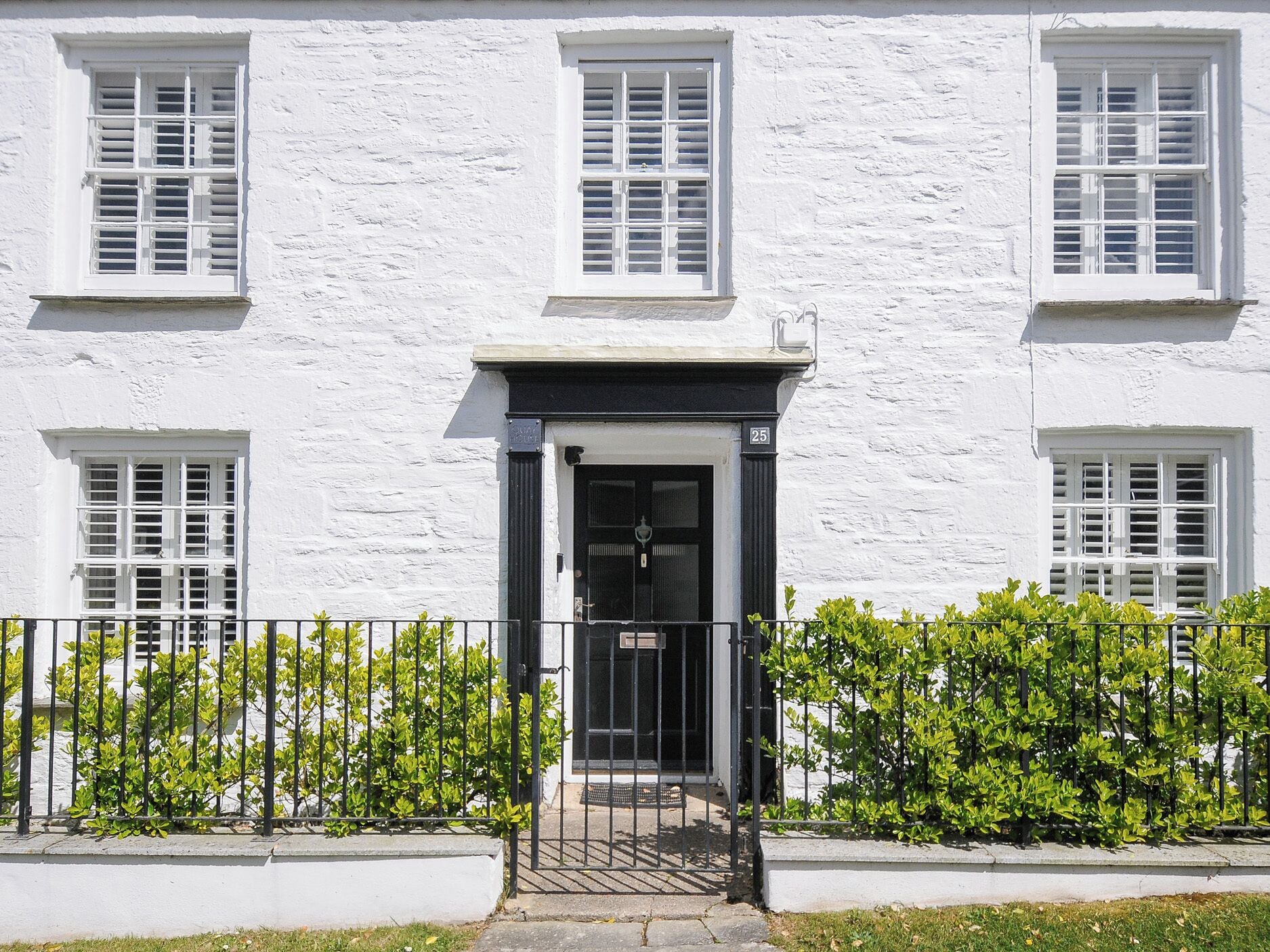 A white building with a black door and windows with shutters.
