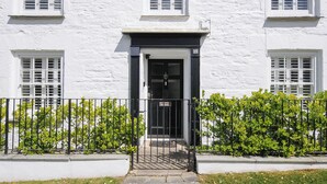 Un bâtiment blanc avec une porte noire et des fenêtres dotées de volets.
