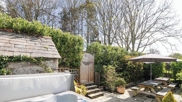 Un bain à remous, une terrasse en bois, des tables de pique-nique et une porte en bois, le tout dans un cadre de jardin.