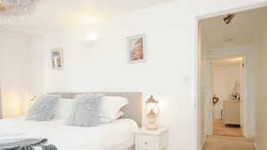 Une chambre à coucher avec un lit, une table de chevet et un couloir menant à une autre pièce.