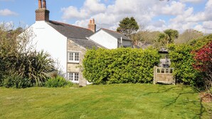Une maison traditionnelle à l’extérieur blanc, dotée d’une cheminée en briques et d’un jardin bien entretenu.