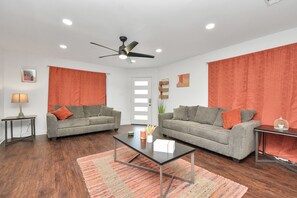 A modern living room with two grey sofas, a coffee table, and a ceiling fan. - ✵Hidden Gem Safari✵| Home w/ Backyard ⮕ Midtown (Houston)