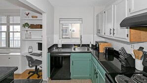 A modern kitchen with white cabinetry, a black countertop, and a window overlooking the city. - 21 first floor cozy condo in the center of DT Atlanta (Atlanta)