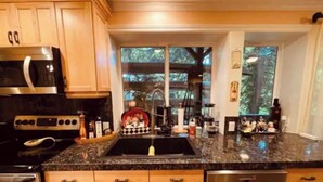 Una cucina con mobili in legno, un forno a microonde in acciaio inossidabile, un lavello e una lavastoviglie.