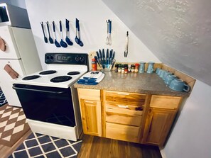 A compact kitchen with a stove, wooden cabinets, and a countertop with various utensils and spices. - Diamond Apartment +Laundry+Gym  - 2 miles to Fort Sill & 1/2 mile to downtown! (Lawton)