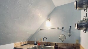 A kitchen with a sink, wooden cabinets, a countertop, and a light fixture above the sink.