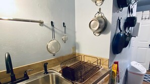 A kitchen with a stainless steel sink, wooden cabinets, and a dish rack.