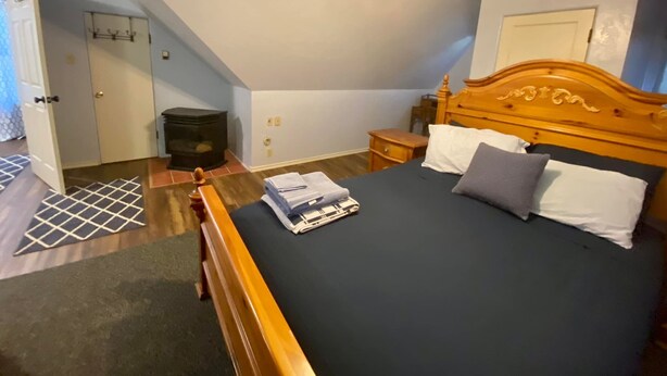 A bedroom with a bed, wooden headboard, bedside table, and a ceiling fan.