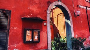 Ein rotes Gebäude mit einem großen Bogenportal, einem kleinen Fenster und einem runden Spiegel darüber.
