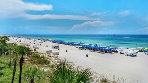 A beach with white sand, blue umbrellas, and clear blue water. - 🌟  Spectacular Sunset Views-Gulf Front-XL Balcony-Pool-Nautical Watch A-11🌟 (Panama City)