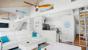 A modern living space with a white sofa, a coffee table, a dining table, and a kitchen area. - 🌟  Spectacular Sunset Views-Gulf Front-XL Balcony-Pool-Nautical Watch A-11🌟 (Panama City)