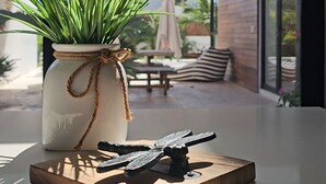 Een modern interieur met een potplant op een tafel, een decoratief metalen object, en uitzicht op een terras buiten met lichtslingers.