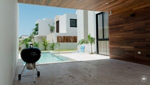 Een modern buitenterras met een zwembad, een barbecue en uitzicht op een woonwijk.