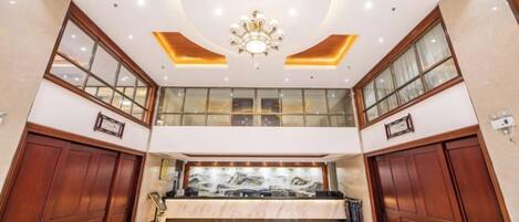 A spacious lobby with a marble floor, a grand chandelier, and a large window with a view.