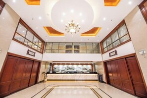 A spacious lobby with a marble floor, a grand chandelier, and a large window with a view. - Binhai Holiday Apartment (Zhanjiang)