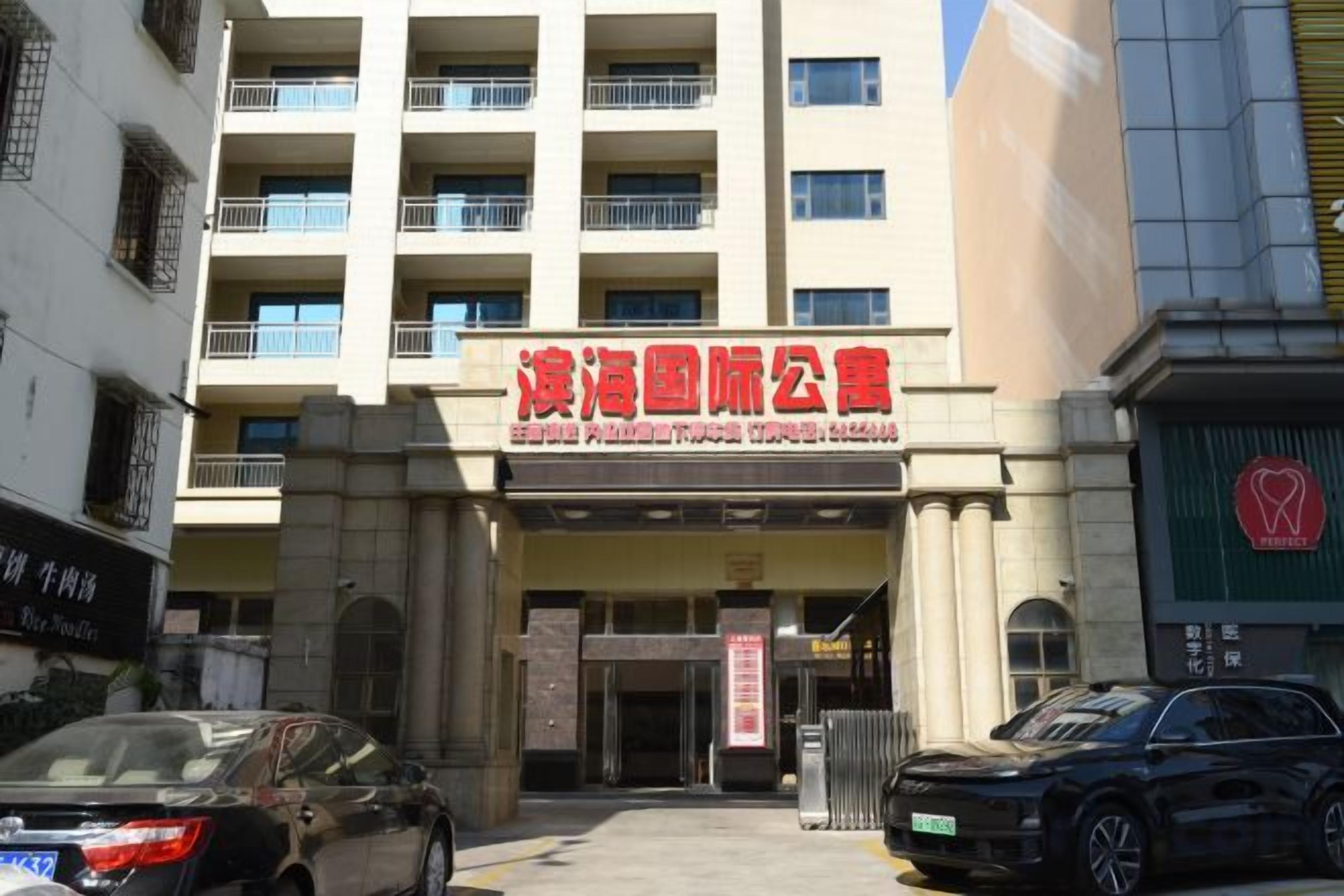 A building with a sign that reads 'Peking University Hospital' and a parking lot with cars.
