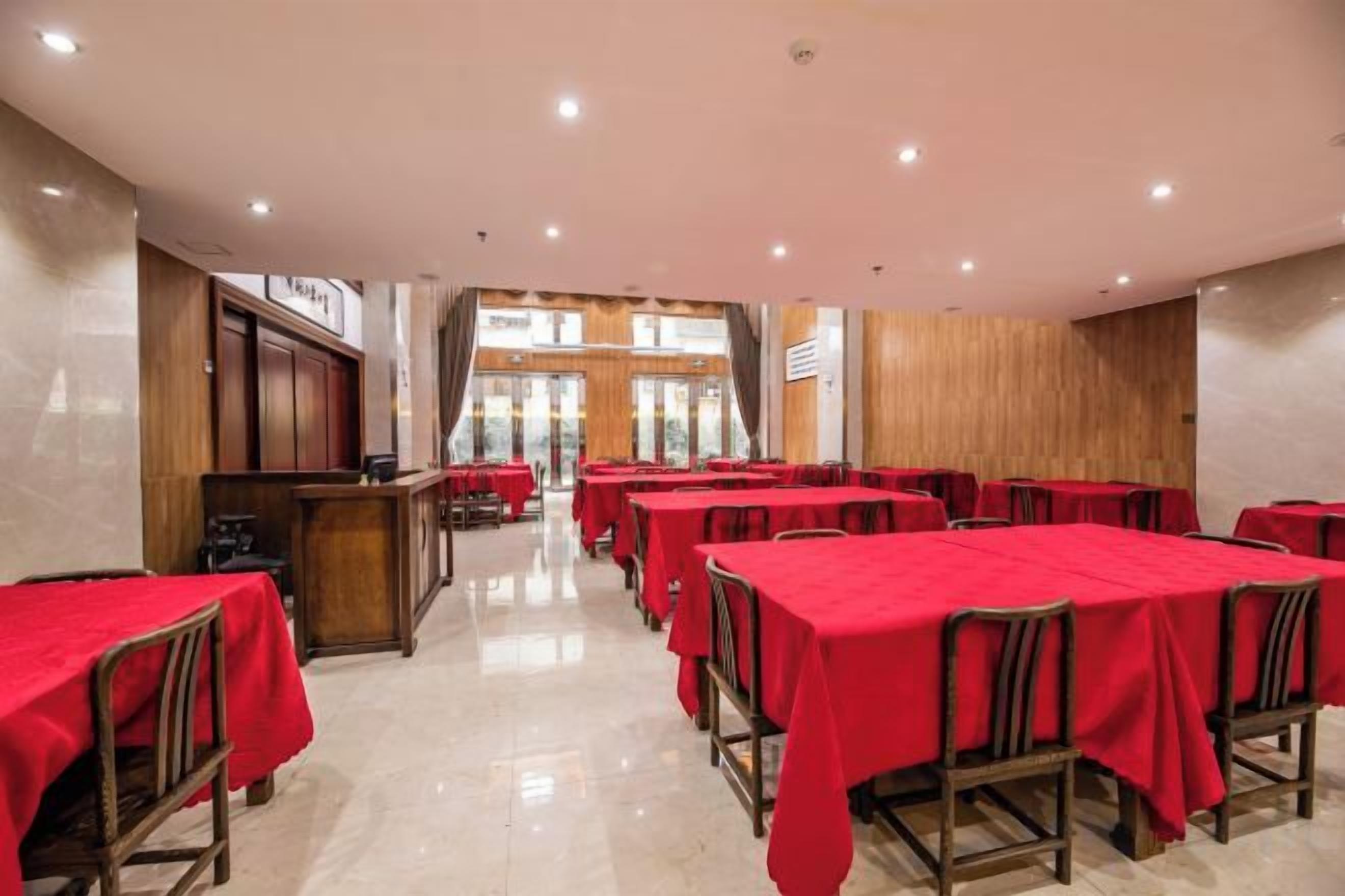 A dining area with multiple tables and chairs, a counter, and a view of the outside through large windows.