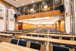 A lecture hall with tiered seating, wooden desks, and black chairs. - Binhai Holiday Apartment (Zhanjiang)