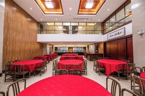 Un comedor amplio con varias mesas redondas, cada una cubierta con un mantel rojo.