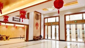 Un vestíbulo amplio con piso pulido, detalles de madera y decoración roja.