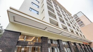 Un hotel de varios pisos con un diseño moderno, que cuenta con una entrada destacada con puertas de vidrio y un letrero que indica que es un vestíbulo con ascensor.