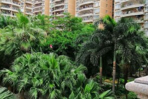 A multi-story residential building with balconies, surrounded by dense tropical vegetation. - Binhai Holiday Apartment (Zhanjiang)
