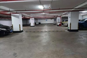 A multi-level parking garage with concrete floors and white pillars, featuring several parked cars.
