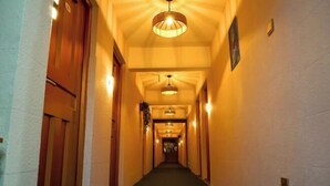 A hotel hallway with a carpeted floor, wooden doors, and pendant lighting. - Fenglai Holiday Hostel (Foshan)
