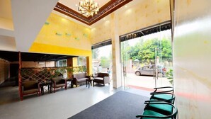 A reception area with a modern chandelier, seating arrangements, and a view of the outside. - Fenglai Holiday Hostel (Foshan)