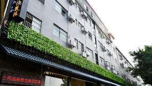 A multi-story building with a modern facade, air conditioning units, and a green ivy-covered awning. - Fenglai Holiday Hostel (Foshan)